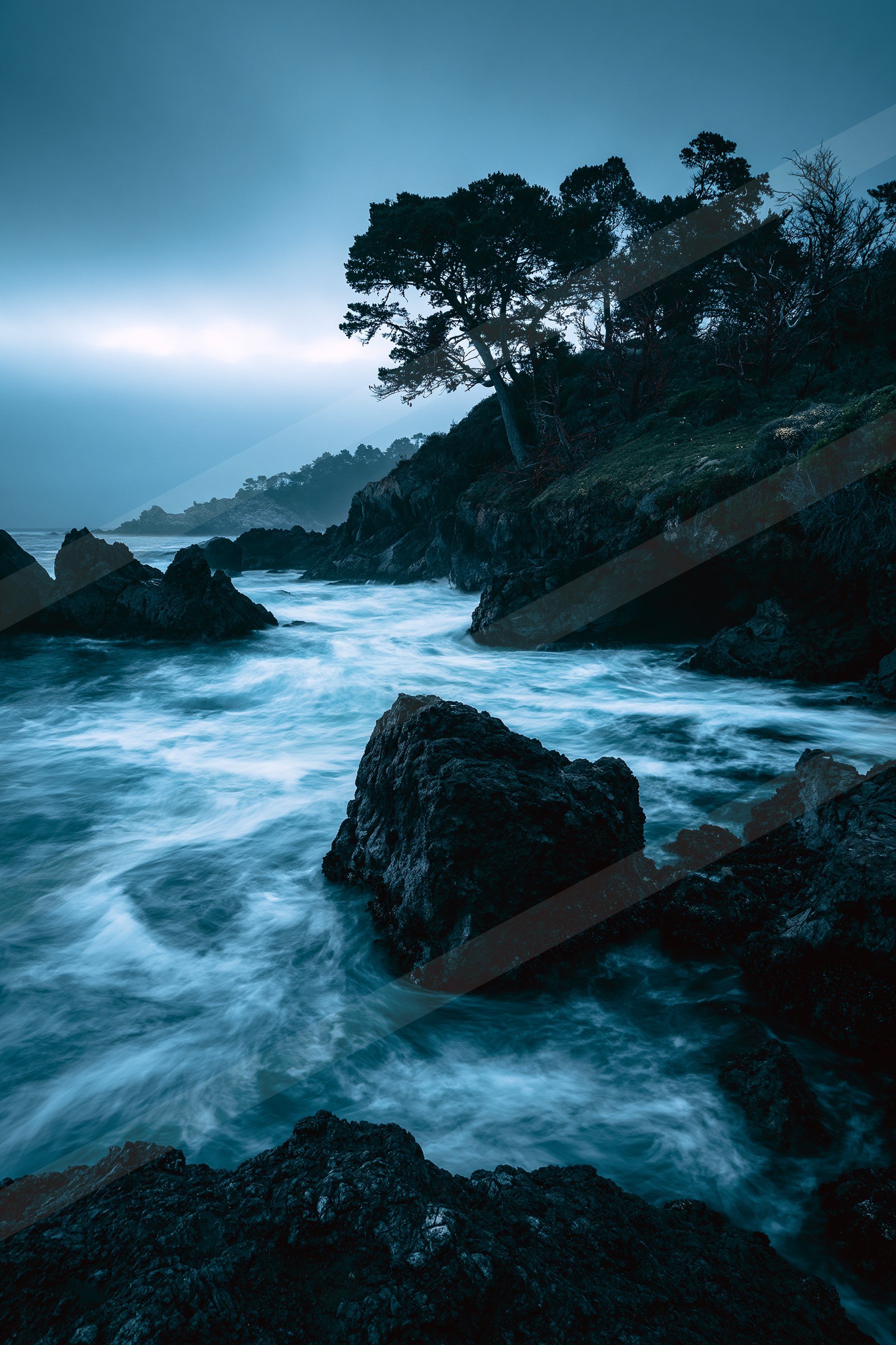 A blue hour long exposure water scene of a coastline, rocks.