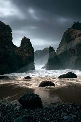 A dramatic long exposure water scene of ocean, beach, mountains.