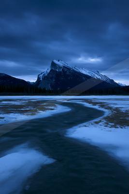 A blue hour long exposure water scene of lake, mountains, river.