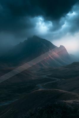 A dramatic long exposure landscape of mountains, storm, valley.
