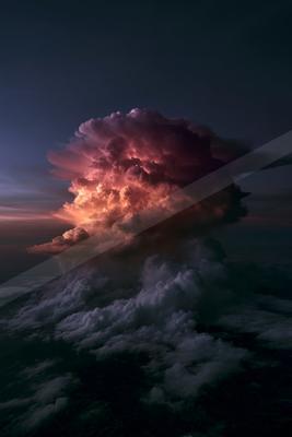 A massive cumulonimbus thunderstorm cloud glows with intense pink, orange, and purple light from within, towering above a layer of lower clouds under a dark blu