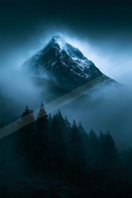 A dramatic landscape of mountains, fog.