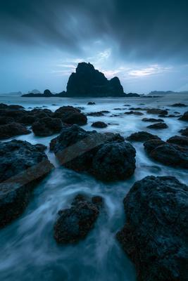 A blue hour long exposure water scene of ocean, rocks.