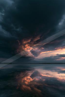 A moody water scene of lake, clouds, storm.