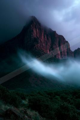 A dramatic landscape of mountains, fog.