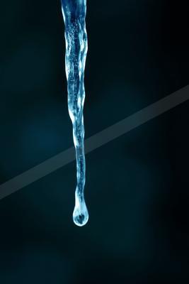 A translucent blue icicle hangs vertically against a dark blurred background with a single water droplet forming at its tip.