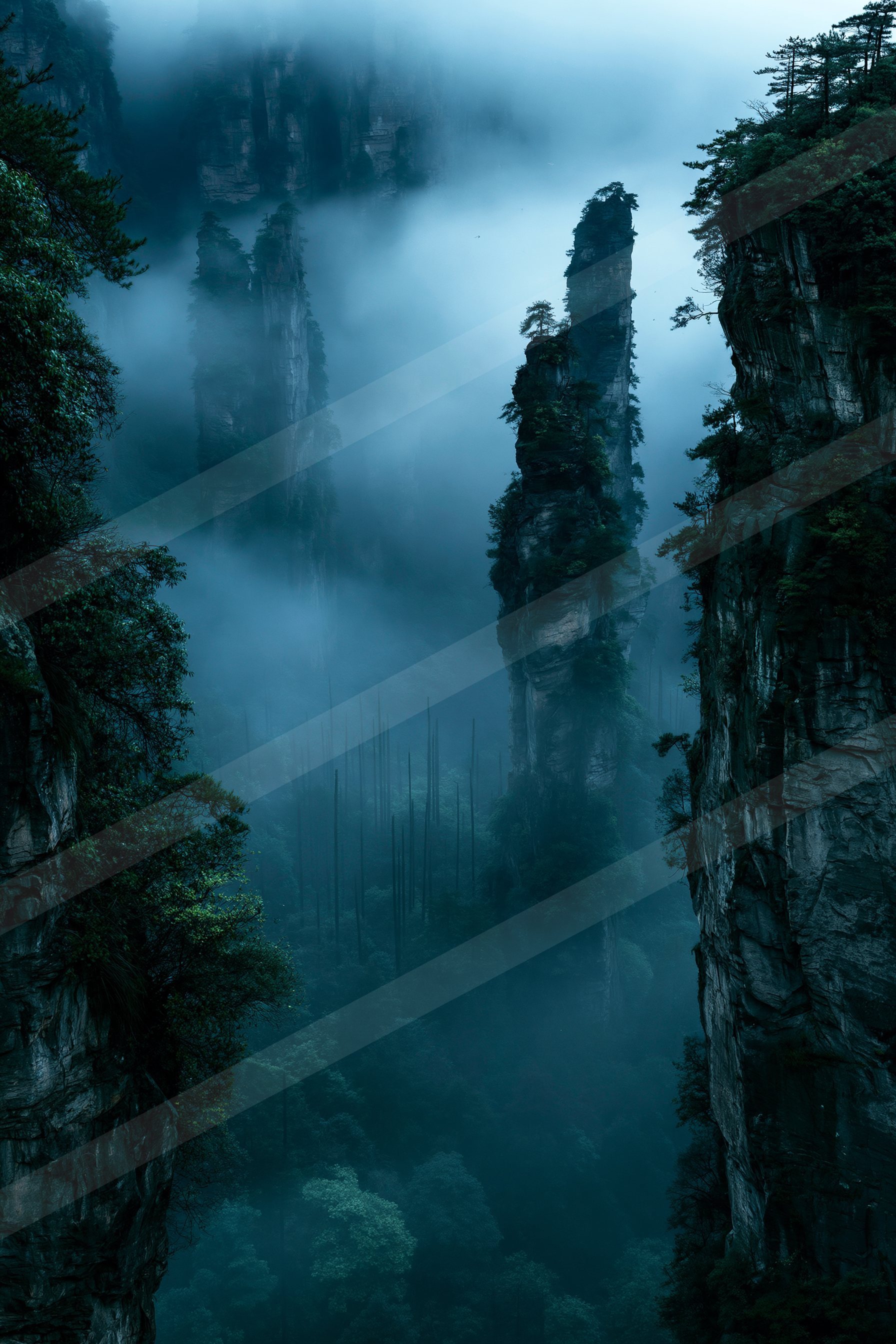 A serene landscape of towering mountain peaks shrouded in mist with dense forest canyons below.