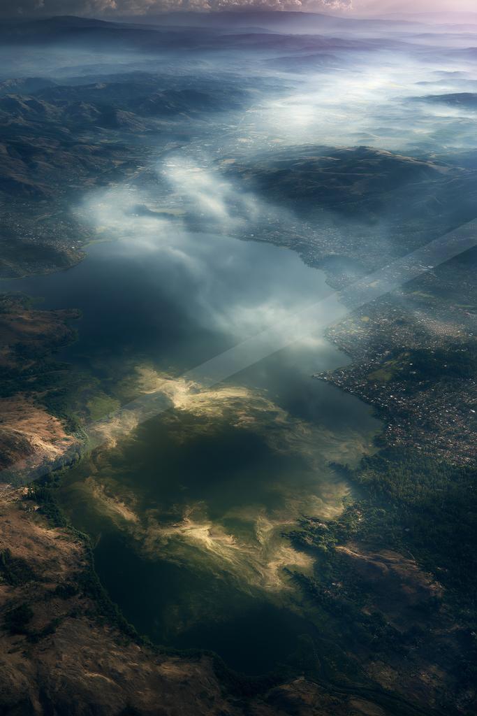 A serene aerial sky scene of clouds, valley, lake.