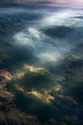 A serene aerial sky scene of clouds, valley, lake.