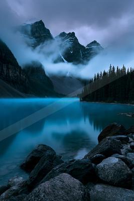 A blue hour long exposure water scene of lake, mountains, fog.