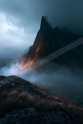 A dramatic landscape of mountains, fog.