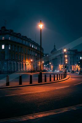 A black-toned moody photograph of traffic light, pole, spotlight.