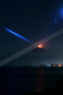 A volcano erupting with glowing lava under a star-filled night sky, featuring a prominent blue star trail and reflections on the water below.