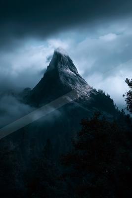 A dramatic landscape of mountains, fog.