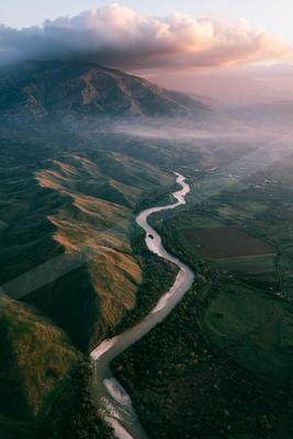 A serene aerial water scene of river, valley, fog.