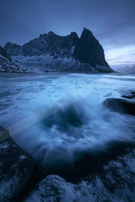 A blue hour long exposure water scene of ocean, mountains, storm.