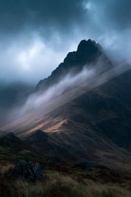 A black-toned moody photograph of mountain tent, valley, castle.