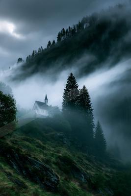 A dramatic architecture photo of church, mountains, storm.