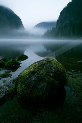 A serene water scene of lake, mountains, waterfall.