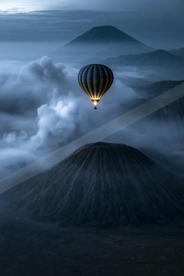 A green-toned moody photograph of balloon, volcano, parachute.
