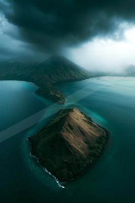 A moody landscape of mountains, ocean, beach.