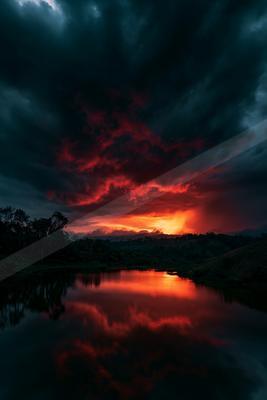 A dramatic water scene of lake, clouds, sunrise.