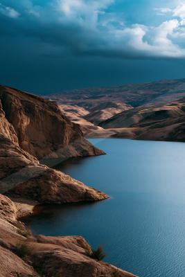A moody landscape of valley, lake, mountains.