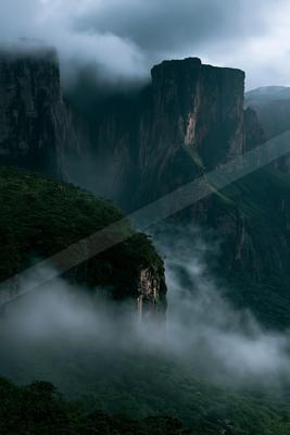 A dramatic landscape of mountains, valley, fog.
