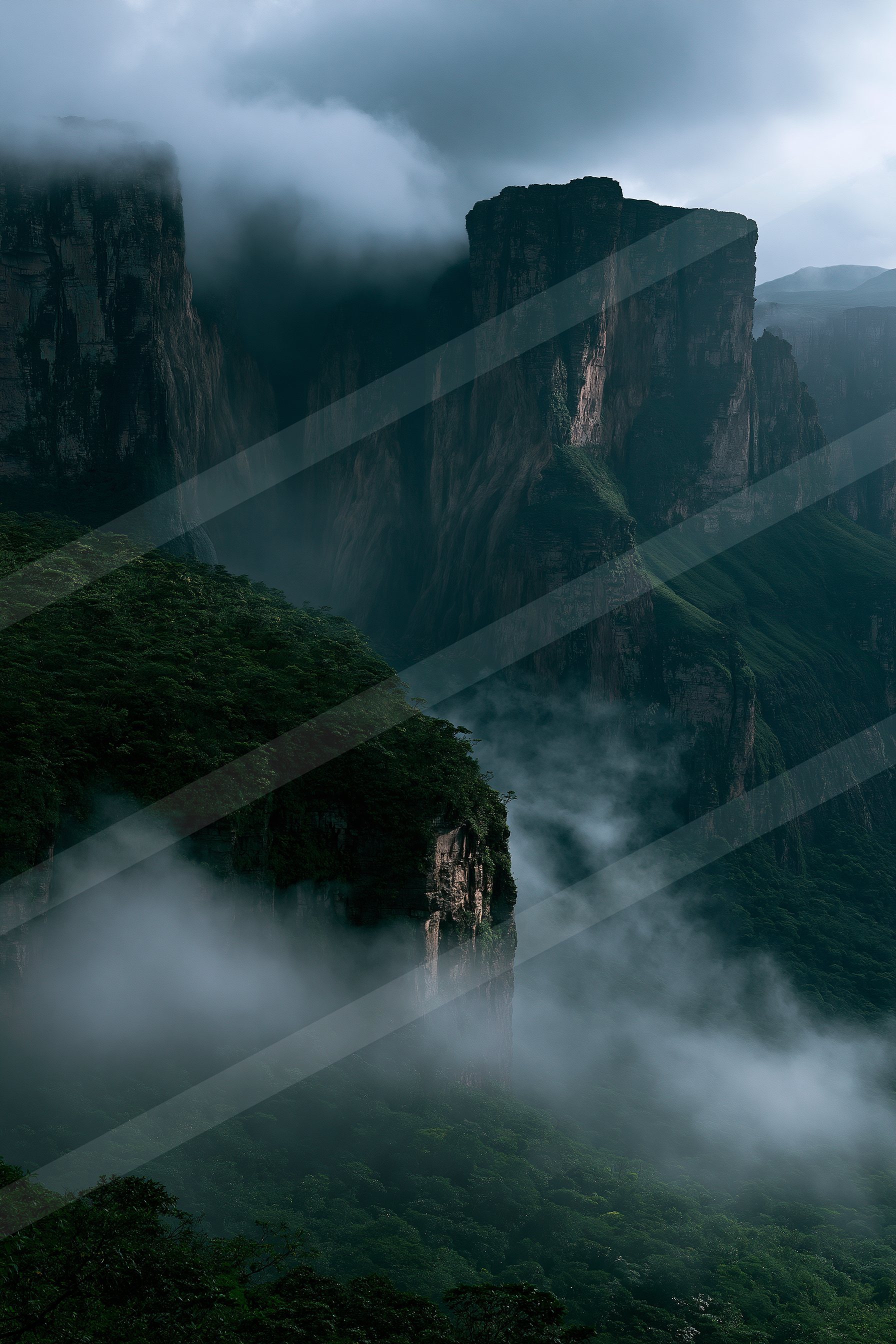 Towering cliffs partially obscured by mist, surrounded by dense green forest under overcast skies.