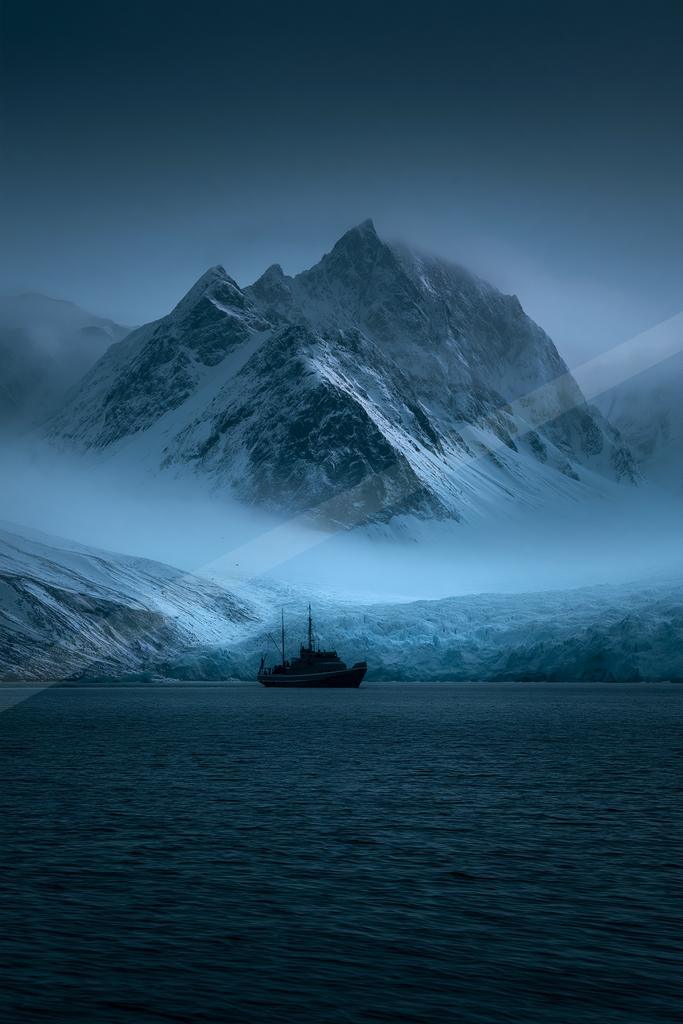 A blue hour landscape of mountains, ocean, fog.