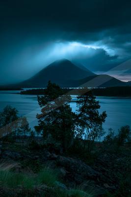 A blue hour sky scene of storm, mountains, clouds.
