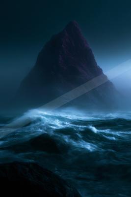 A dramatic water scene of ocean, storm, mountains.