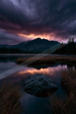 A blue hour water scene of lake, mountains, sunset.
