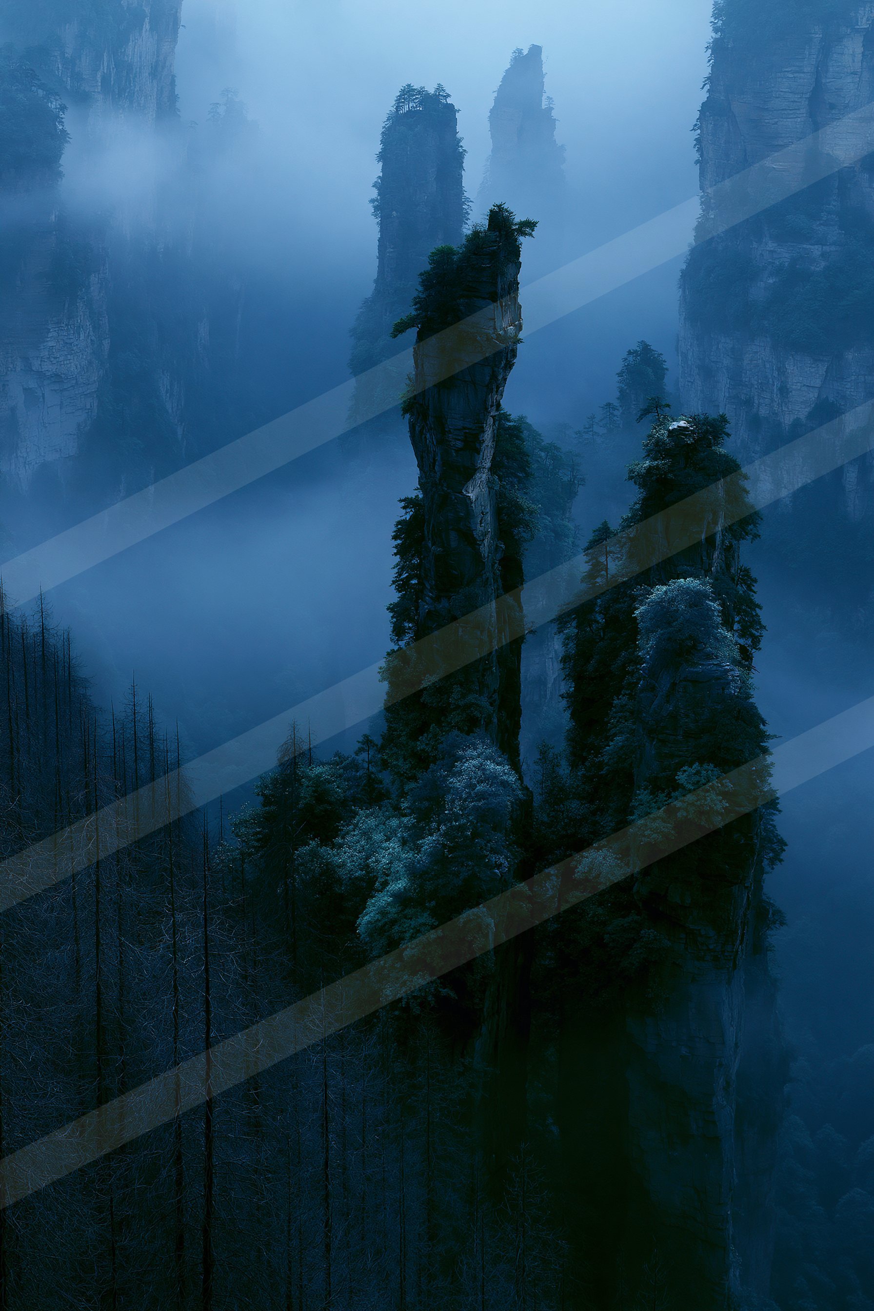 A serene landscape featuring towering rock formations shrouded in mist, surrounded by dense evergreen trees.