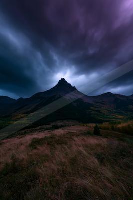 A dramatic landscape of mountains, storm, clouds.