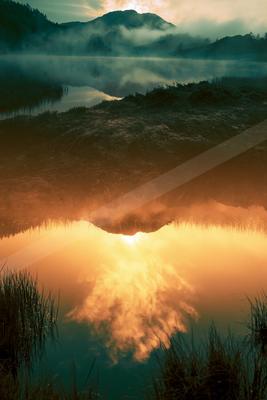 A serene long exposure water scene of lake, sunrise, fog.