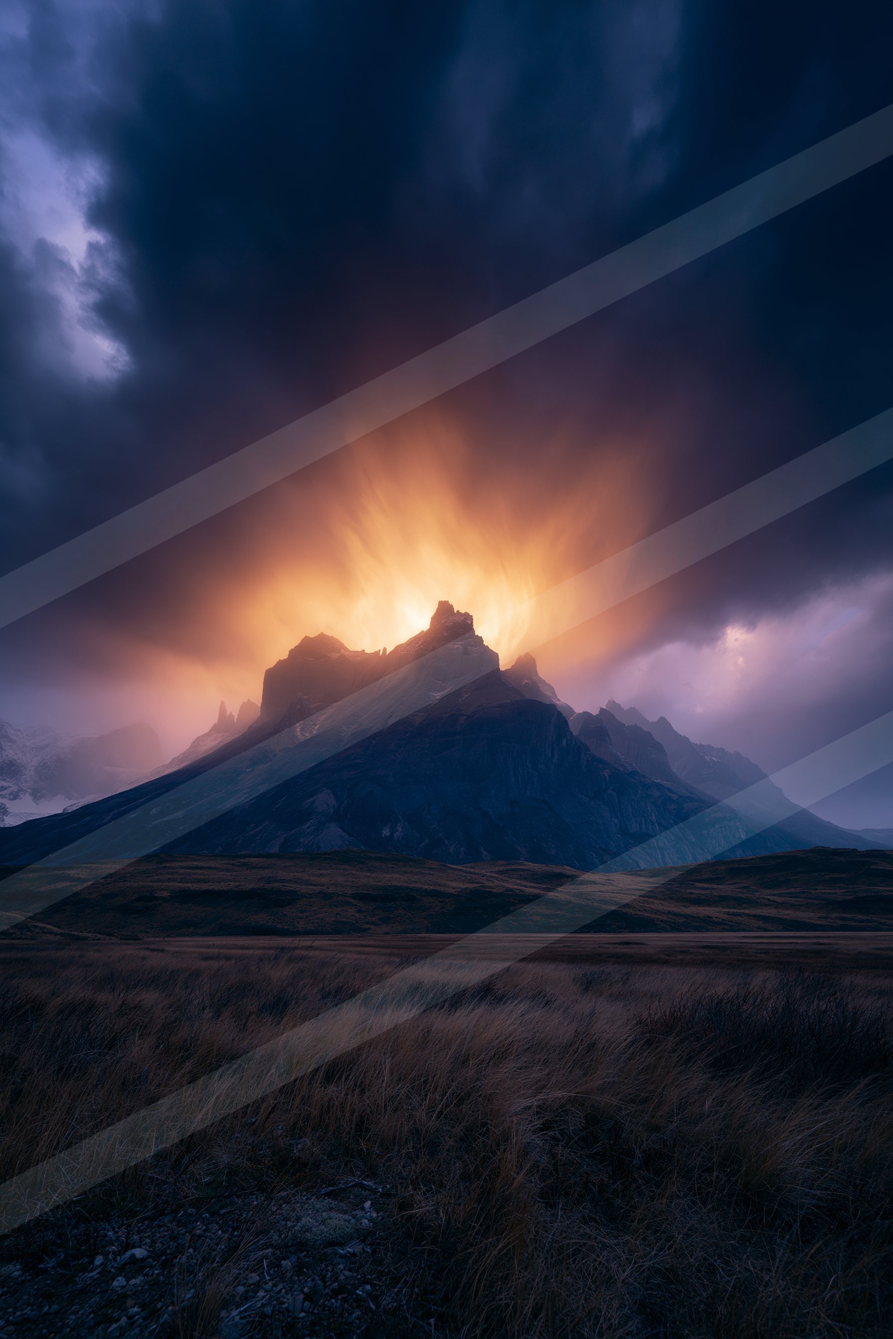 A majestic mountain peak silhouetted against a vibrant, stormy sky filled with dramatic clouds and warm backlighting.