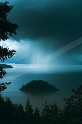 A blue hour sky scene of storm, mountains, lake.