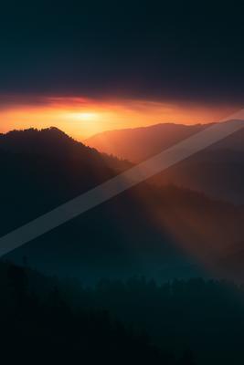 A moody landscape of mountains, sunrise, valley.