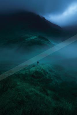 A solitary person walks along a grassy ridge enveloped in thick blue-green fog with dark mountains looming in the background under a moody sky.
