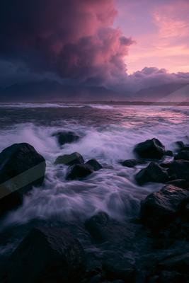A blue hour long exposure water scene of ocean, storm, rocks.
