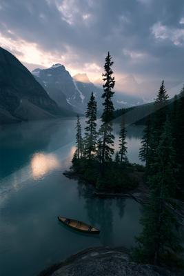 A black-toned moody photograph of canoe, lakeside, paddle.