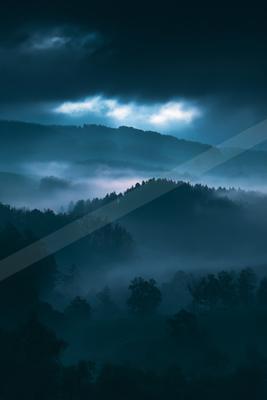 A blue hour high contrast landscape of a rolling hills, fog.