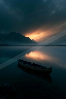 A black-toned moody photograph of canoe, paddle, lakeside.