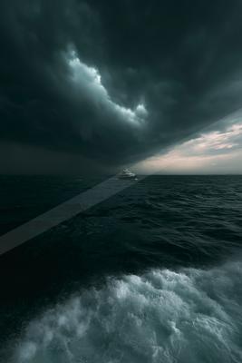 A luxury yacht sails across a dark, turbulent ocean beneath a sky filled with heavy storm clouds, with white-capped waves in the foreground.