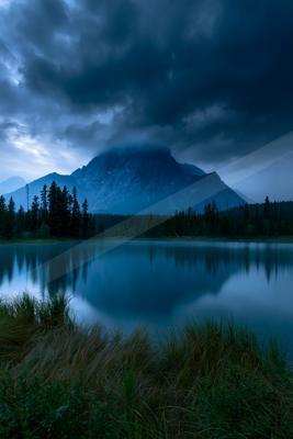 A blue hour long exposure water scene of lake, mountains, storm.