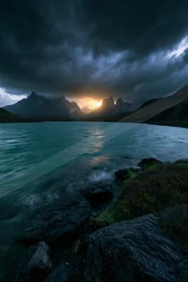 A blue hour sky scene of storm, lake, mountains.
