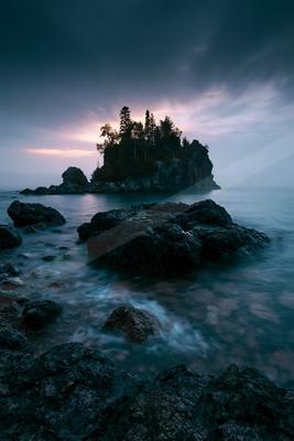 A blue hour long exposure water scene of ocean, sunrise, rocks.
