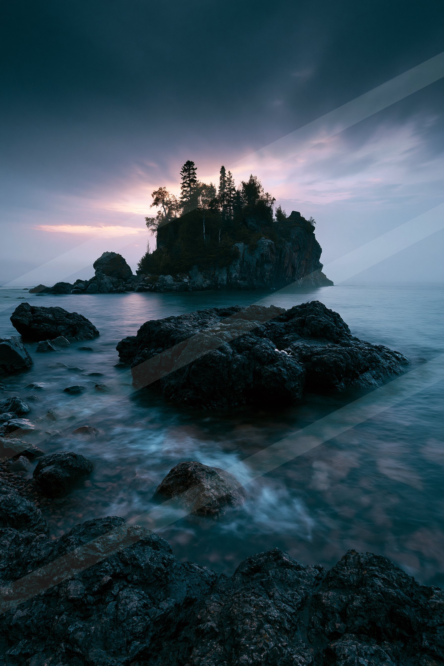 A blue hour long exposure water scene of a coastline, rocks.