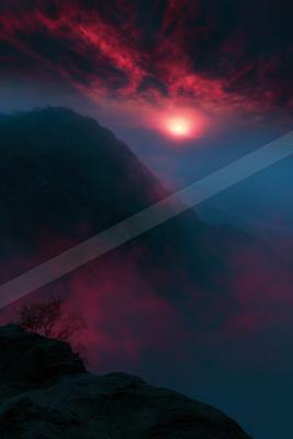A dramatic sky scene of sunrise, mountains, clouds.
